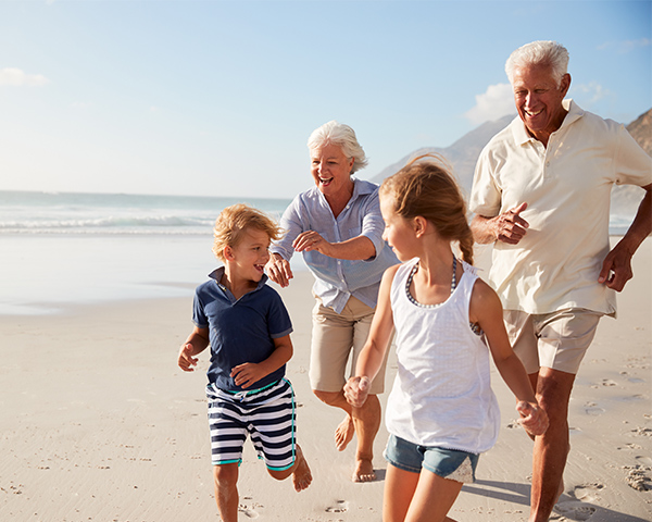 grandparents running on the beach with their grandkids successful retirement